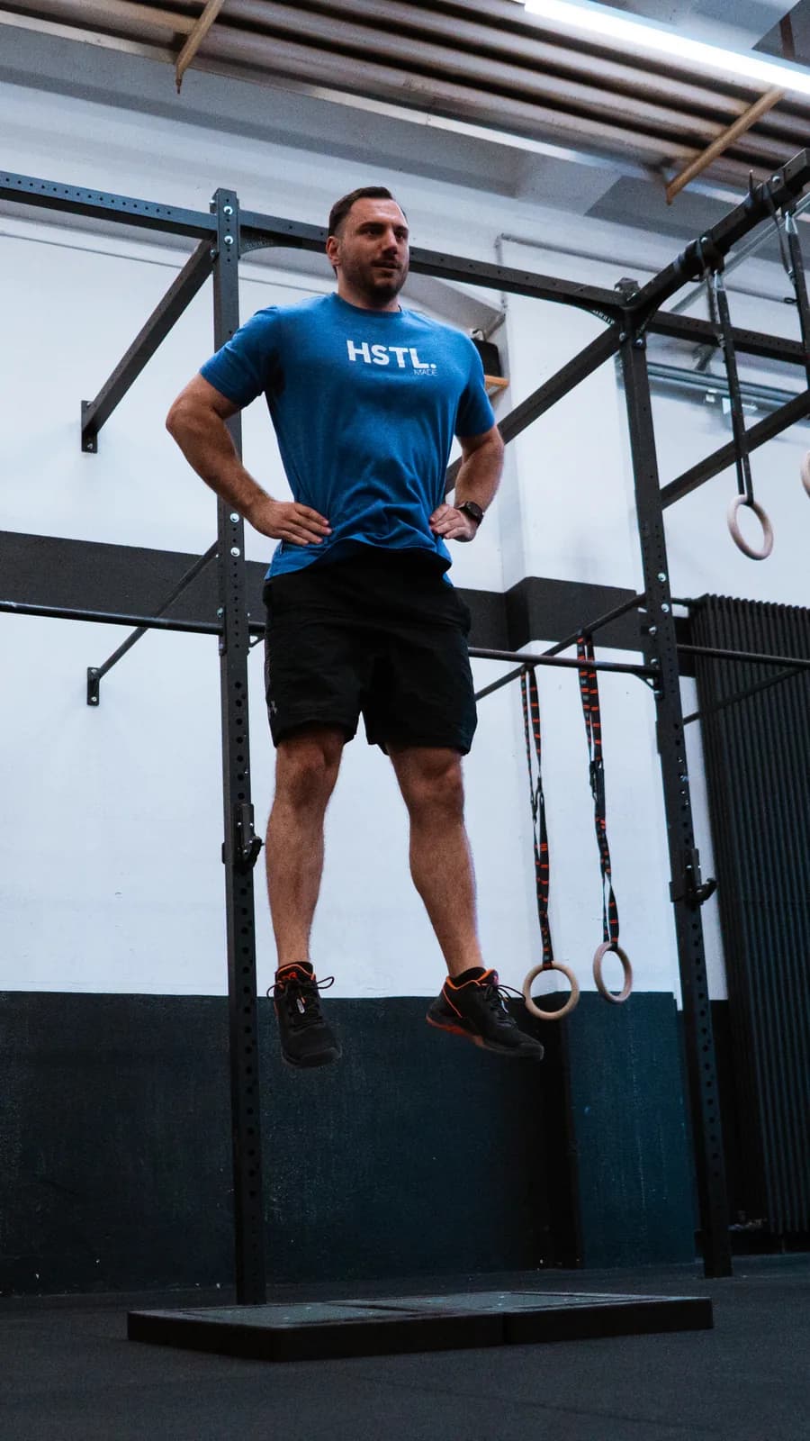 Athlet in der Flugphase eines Countermovement Jumps über zwei Kraftmessplatten in einer Trainingshalle.